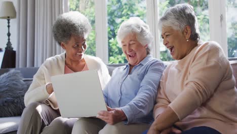 Drei-Verschiedene-ältere-Frauen-Nutzen-Gemeinsam-Einen-Laptop-Und-Sitzen-Zu-Hause-Auf-Der-Couch