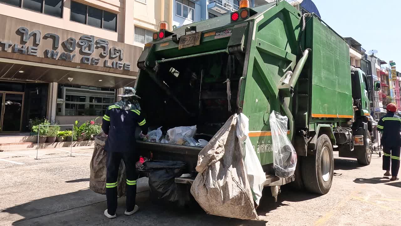 trabajadores cargando basura en un camión de basura