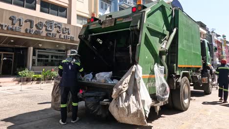 workers loading trash onto a garbage truck