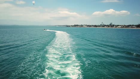 aerial-drone-shot-of-fast-boat-travelling-away-from-the-camera,-created-a-long-boat-track