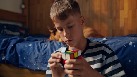 boy solving a rubik's cube in his bedroom
