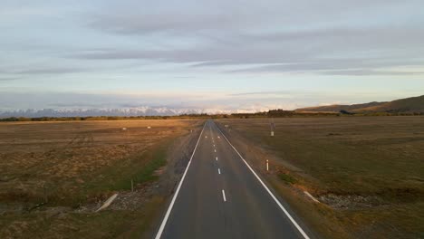 Straight,-endless-freedom-road-leading-towards-majestic-mountains-in-golden-morning-glow