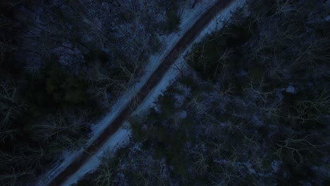 Smooth-nighttime-drone-footage-of-a-beautiful-road-through-a-snowy-winter-forest-in-the-Appalachian-mountains-during-winter-in-New-York's-Hudson-Valley-in-the-Catskill-Mountains-sub-range