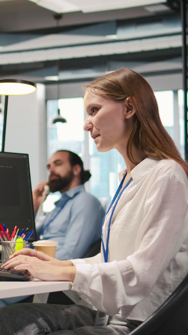 Vertical video Happy female programmer dancing on office desk chair