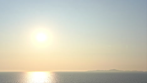 수평선 바로 위의 밝은 노란색 태양이 바다에 반사됩니다.