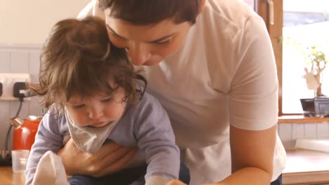 madre usando tableta digital mientras varía a su bebé