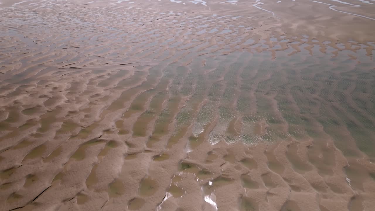 Flying over rippled tidal sands and clear seawater pools on a sunny day. Fleetwood, Lancashire, UK.
