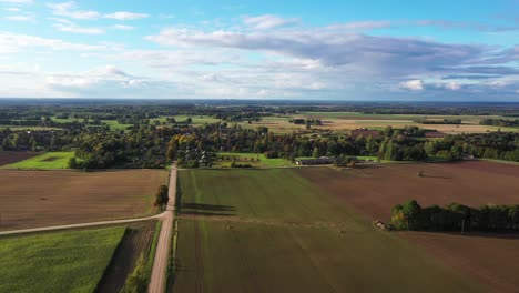 Endless-farm-flatlands-and-iconic-small-countryside-village,-aerial-view