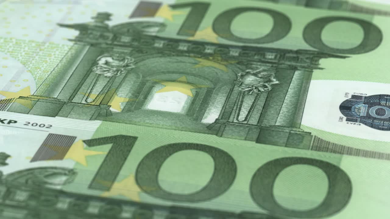 An extreme close-up camera shot panning over multiple 100 Euro bank notes - seamless looping