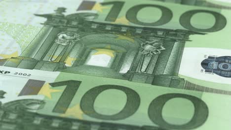 an extreme close-up camera shot panning over multiple 100 euro bank notes - seamless looping