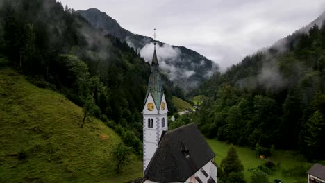 slovenia small town surrounded by misty pine forest mountains aerial drone 4