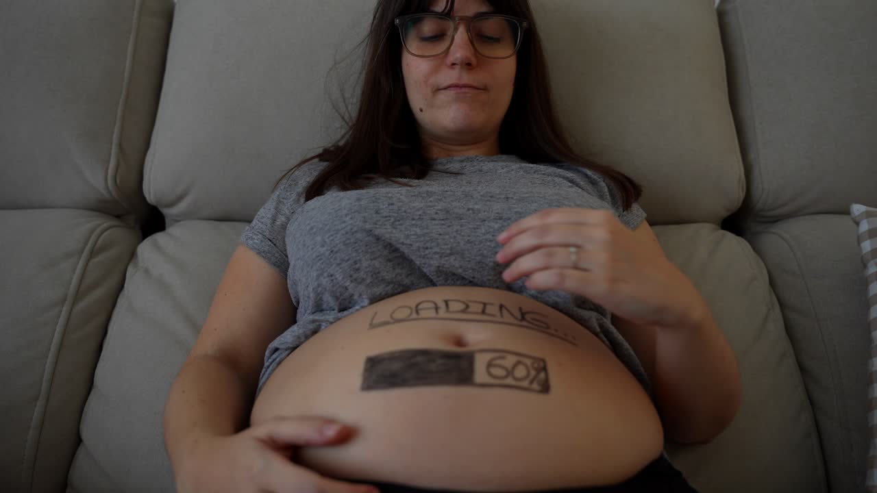 Giovane donna incinta che guarda e tocca la sua pancia sul divano