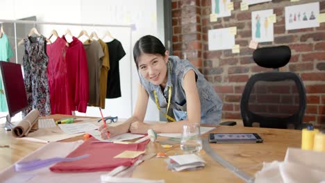 portrait of happy asian asian female designer at work in fashion design studio in slow motion