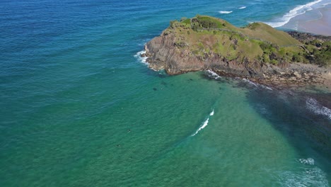 rugged landscape of norries headland and surfers floating at norries beach in nsw, australia