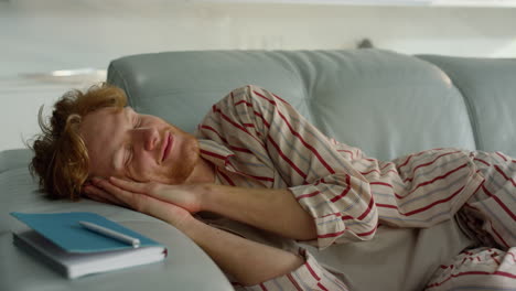 relaxed guy sleeping sofa in pajamas closeup. smiling freelancer enjoy daydream