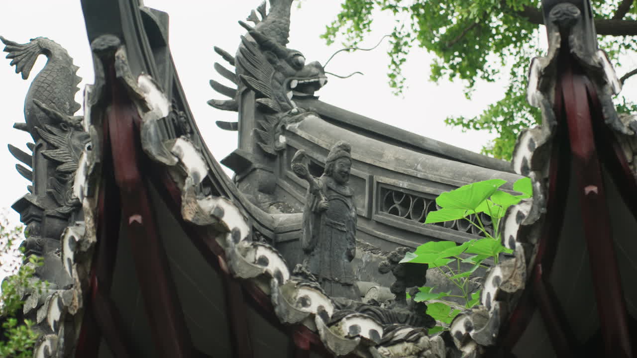 Sculture di draghi su un tetto ornato di tempio, tegole in argilla invecchiate e bestie scolpite sul colmo incorniciate da un vivido fogliame verde, primo piano su grondaie e dettagli in ceramica, atmosfera storica serena ideale per la cultura.
