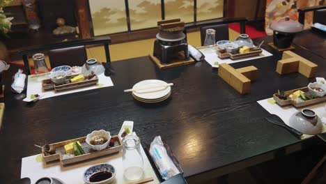 ryokan dining room with set places for many rooms, hot pots ready for sukiyak