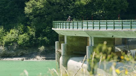 mountain biker rides across a dam on a sunny day