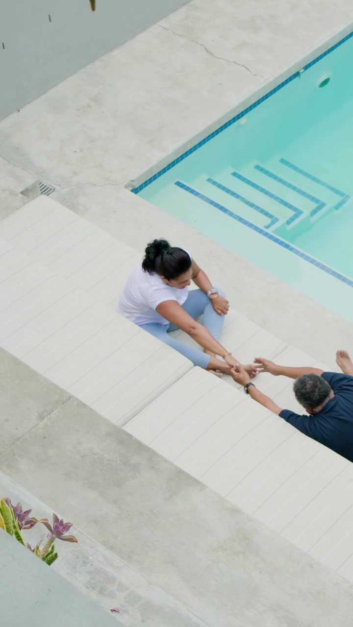 Vertical video: Reacting to man's reach, woman stretching foot with aid on pool steps, copy space