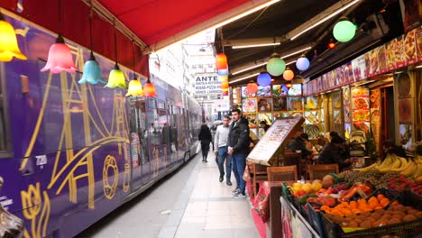 street scene in istanbul with a tram passing by a restaurant with people eating and walking by