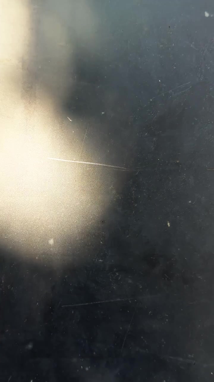 Scratched dark surface with warm golden light orb