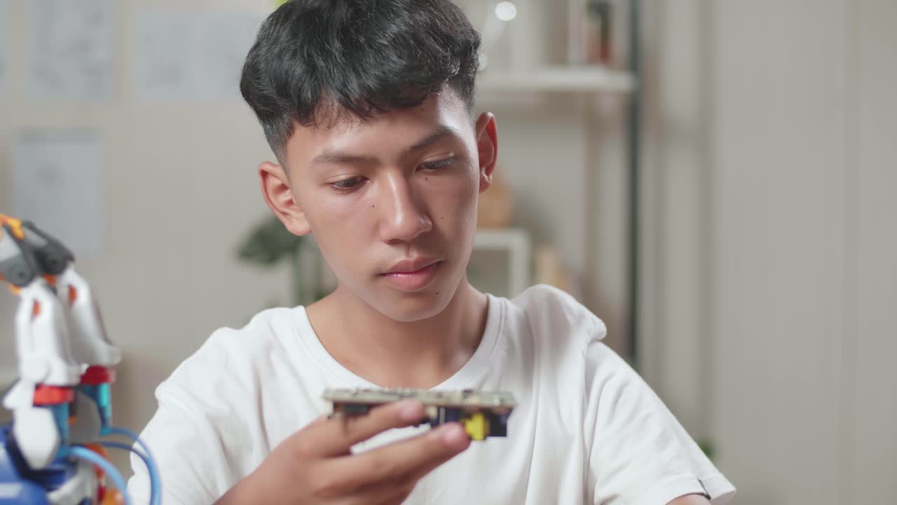 집에서 사이보그 손을 수리하는 동안 회로판을 들고 고치는 아시아 소년의 클로즈업