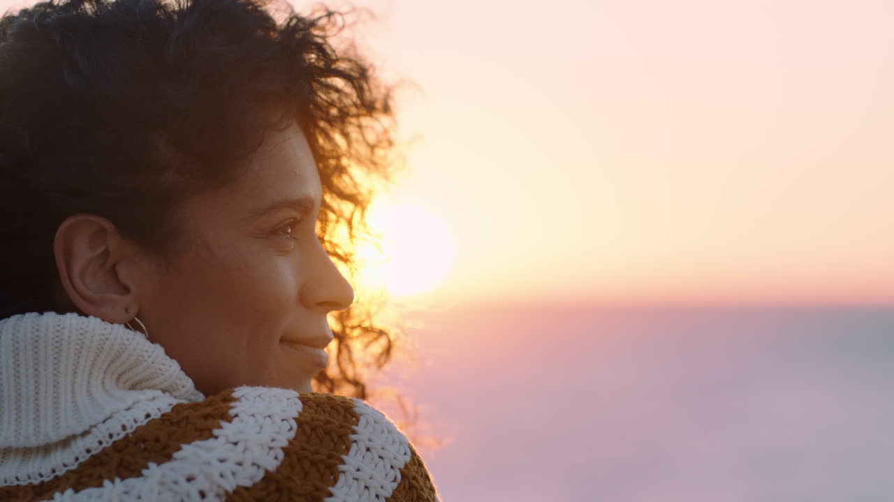 portrait of beautiful hispanic woman enjoying peaceful seaside at sunset exploring mindfulness contemplating spirituality with wind blowing hair