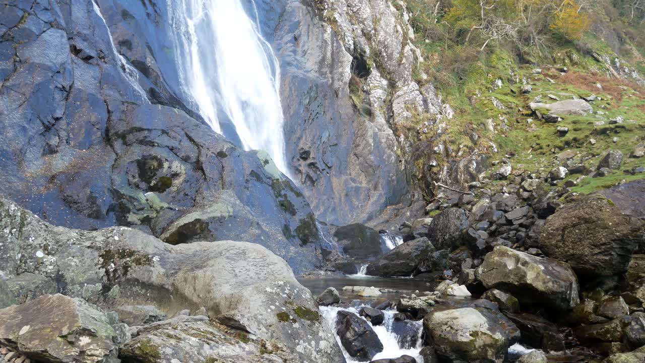 cascada rocosa que desemboca en rocas irregulares del río y cantos rodados a la izquierda de dolly