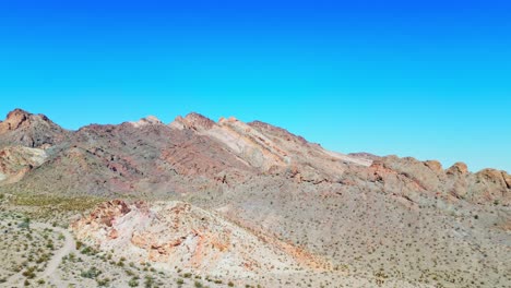 Montañas-Rocosas-Contra-El-Cielo-Azul-En-La-Ciudad-Fantasma-De-Nelson,-Nevada,-EE.UU.---Toma-Panorámica-Aérea