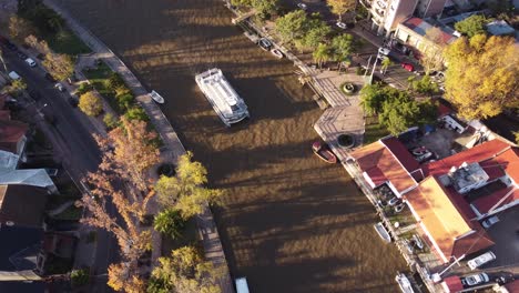 Aerial-view-of-white-passenger-boat-on-waters-of-small-canal-in-Tigre,-Buenos-Aires