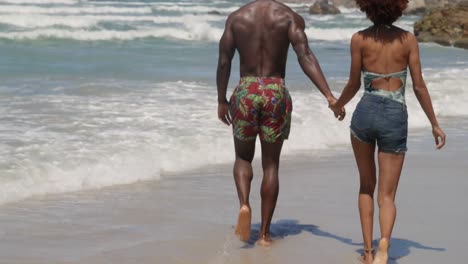Couple-walking-together-on-beach-in-the-sunshine-4k