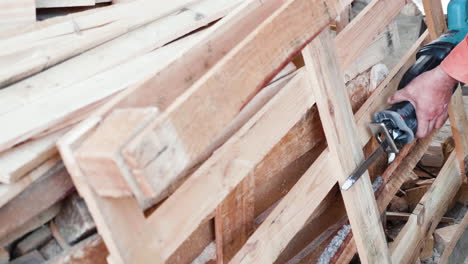 man in a wooden pallets factory using a electric saw