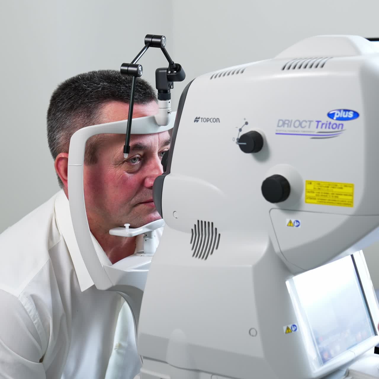 Male patient sitting at the apparatus for eyesight examination. Doctor's hand moving the handle of the equipment