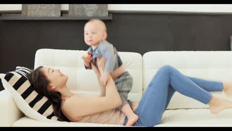 happy mother and baby playing on a sofa