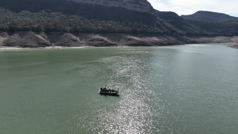 Fisherman-boat-working-in-Sau-reservoir-in-Catalonia,-severe-drought-water-level