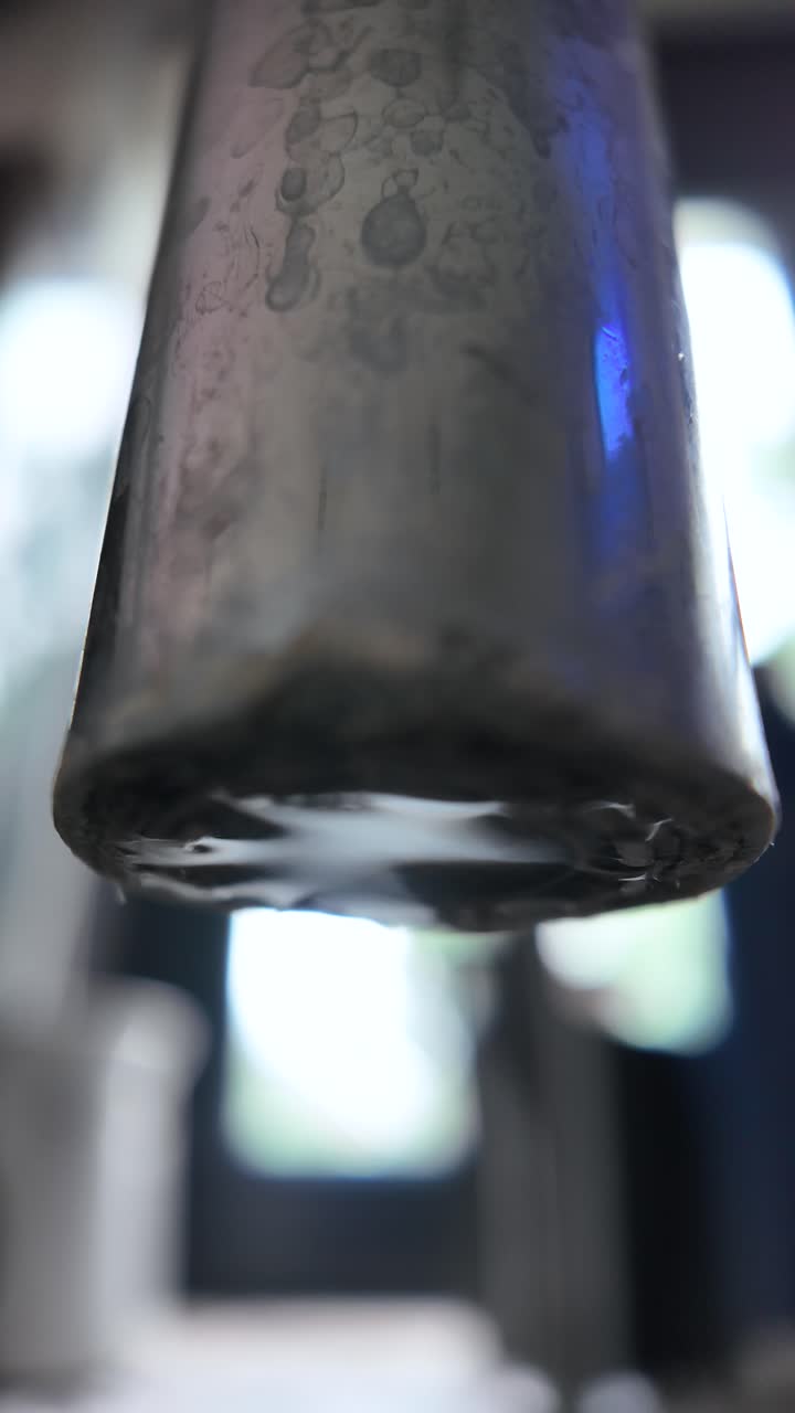 A detailed view of a rusted faucet dripping water, emphasizing texture and motion. Vertical Video