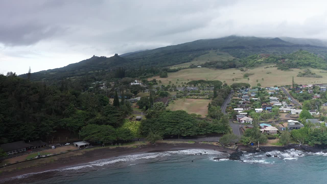 Aerial wide reverse pullback shot of the small Hawaiian village of Hana Town on the windward side of Maui in Hawai'i