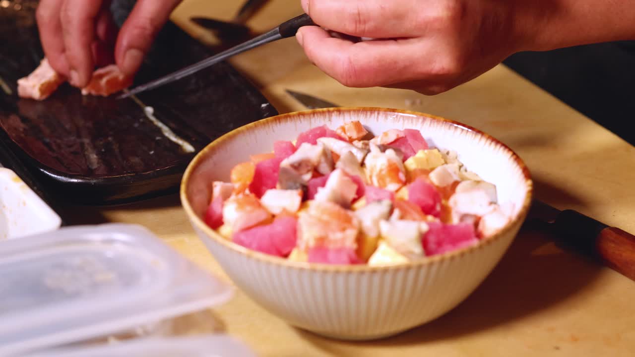 新鮮な海鮮丼を盛り付けるため、手と箸を使うシェフのクローズアップ写真。