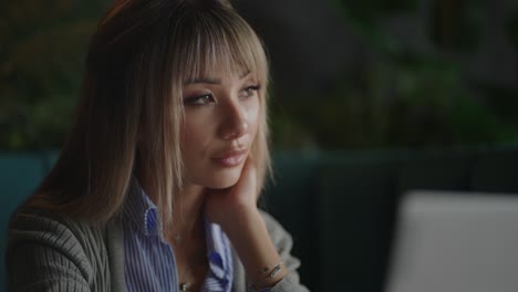 retrato de una hermosa, joven y atractiva mujer asiática está sentada y parece preocupada y seria mientras reflexiona frente a su computadora portátil durante el día.