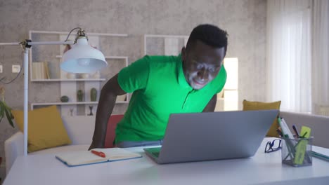 cheerful and happy african young man doing his job with pleasure and love in his home office.