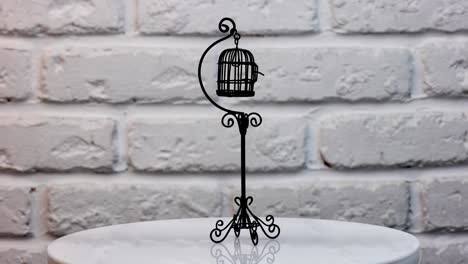 small black cage for a canary at the rotating table. fine toy bird cage for the decoration of doll's house. close up.