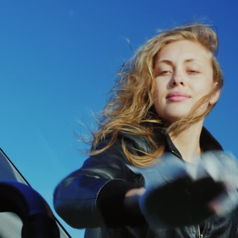 Portrait-Of-A-Young-Attractive-Woman-Who-Rubs-The-Windshield-Of-Her-Car