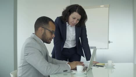 Smiling-colleagues-working-with-laptop-in-office