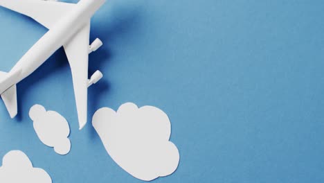 close up of white airplane model with white clouds and copy space on blue background