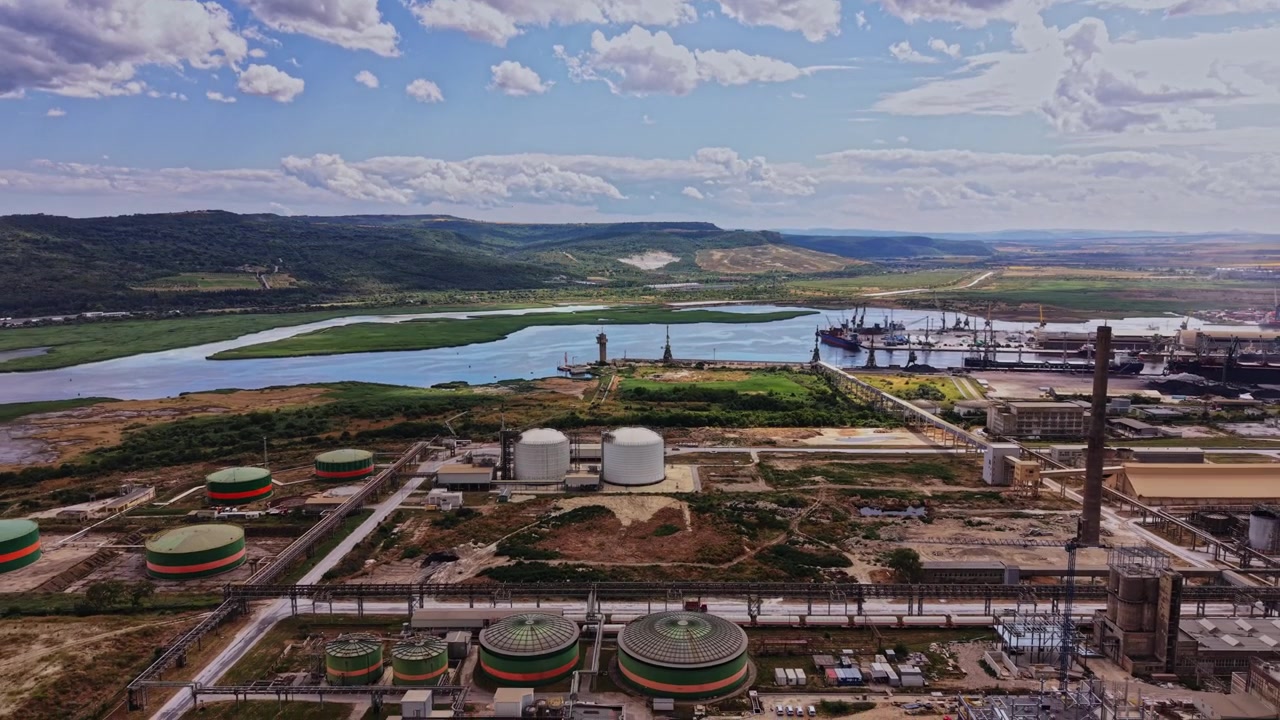 Vista de zona industrial cerca de un río con barcos y paisaje verde