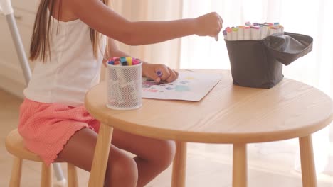 girl drawing with markers at a table