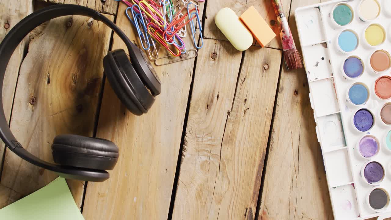 vídeo de pinturas de acuarela, auriculares y artículos de papelería en tableros de madera con espacio para copiar