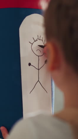 little girl draws sad face on punching bag in play room close rare view. child visualizes negative emotions and reduces stress with sports equipment