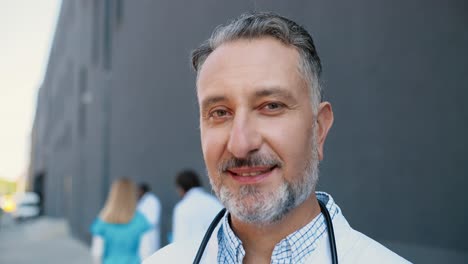 portrait of gray-haired doctor with stethoscope looking at camera and smiling