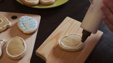 close-up of women's hands apply icing to cookies using a cooking syringe. cookies in the form of an easter egg